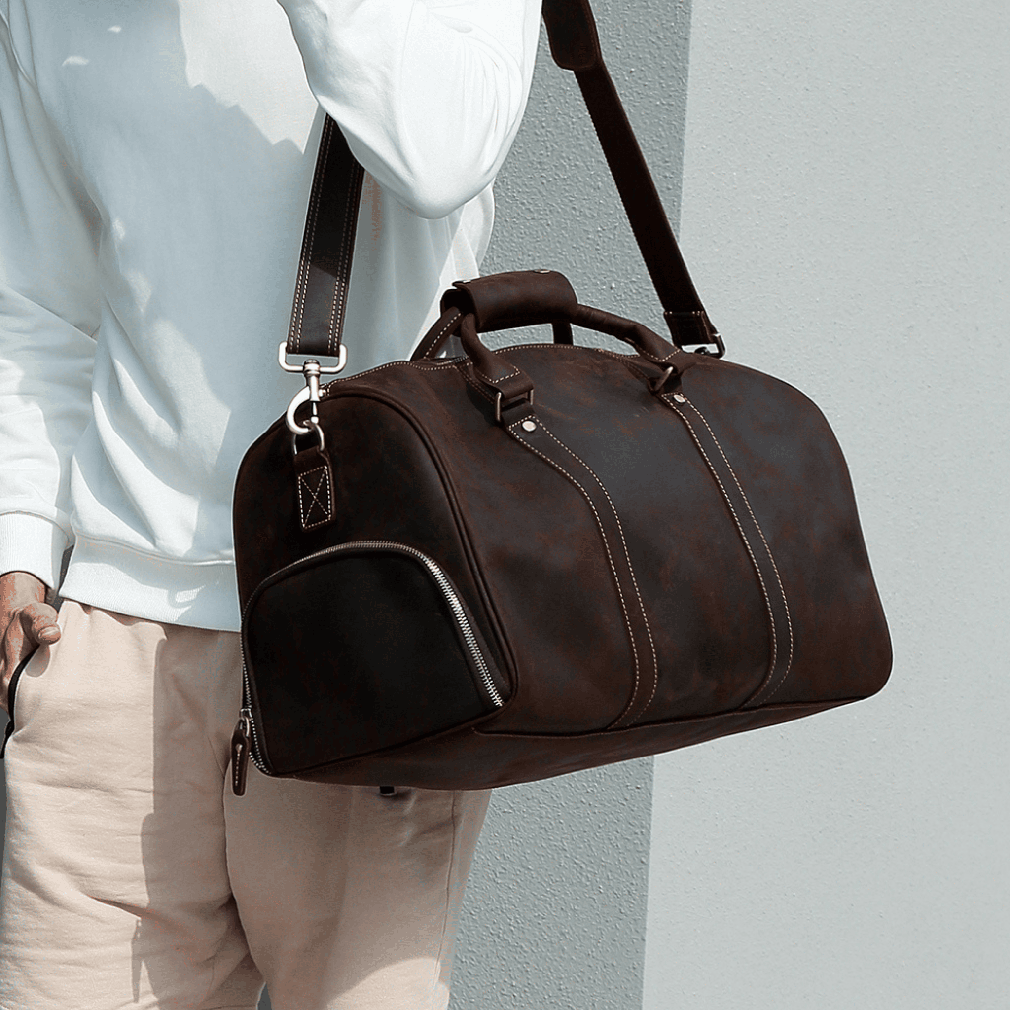 stylish man wearing a brown duffle bag over his shoulder