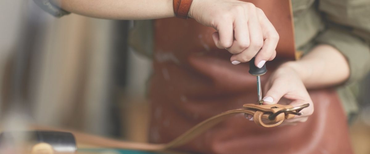 lady tightening screws on leather belt in workshop- BeltUp Leather Co.
