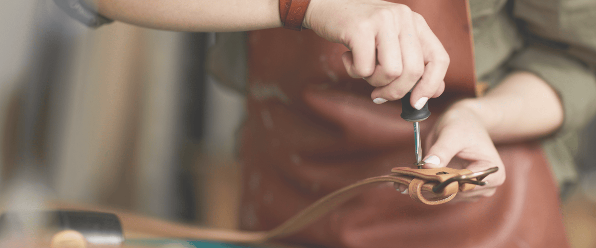 lady tightening screws on leather belt in workshop - BeltUp Leather Co.